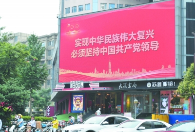 6月20日，南京街头各类楼宇电子屏，街边花坛、灯杆上出现庆祝中国共产党成立100周年宣传标语，营造出浓厚的喜庆氛围。图为新街口商圈电子大屏打出的巨幅标语。南报融媒体记者 董家训摄