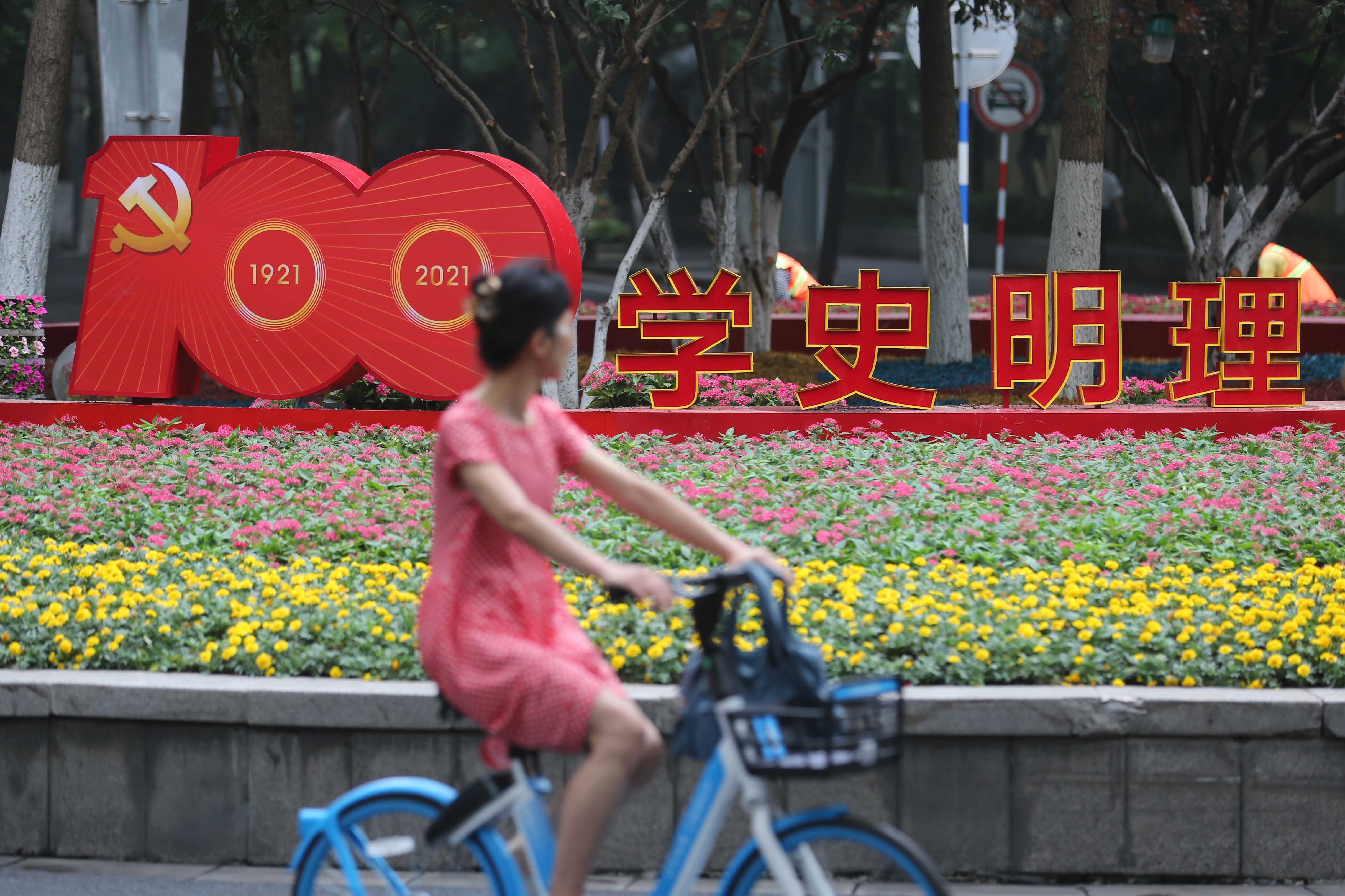 6月19日，南京市民从宁海路转盘走过。连日来，南京街头“庆祝中国共产党成立100周年”主题花卉景观陆续亮相，营造出浓浓的喜庆氛围。南报融媒体记者 徐琦摄